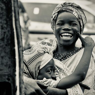 Photo en noir et blanc d'une femme souriante portant son enfant