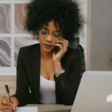 Photo d'une femme au téléphone prise de note devant ordinateur