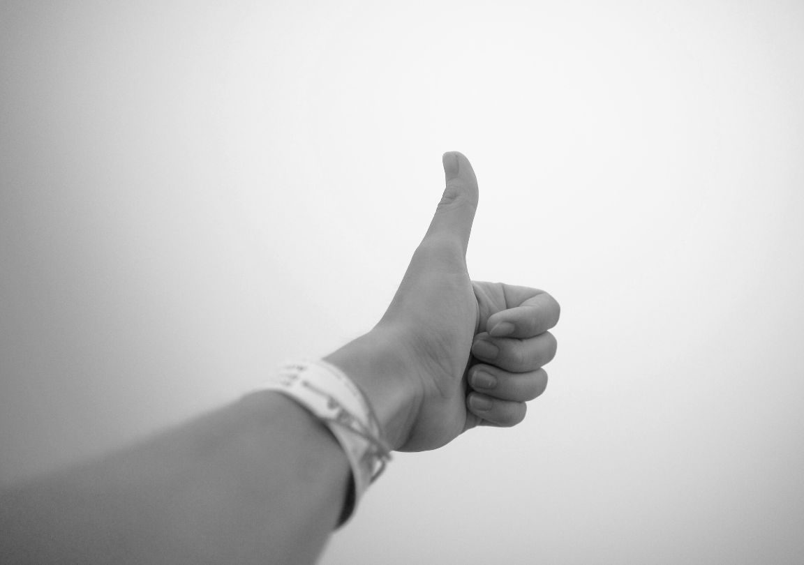 Photo en noir et blanc d'une main avec le pouce levé témoignage positif