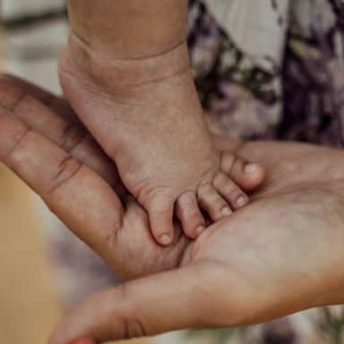 Pied de bébé posé sur la main d'un adulte
